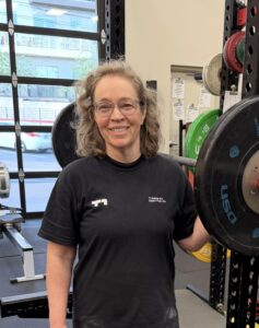 Woman standing next to squat rack