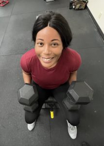 Woman sitting on bench holding dumbbells