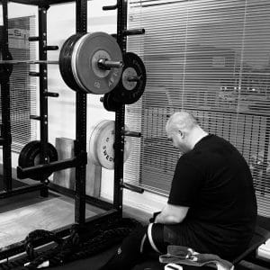 Lifter sitting on a bench, resting in between heavy squats