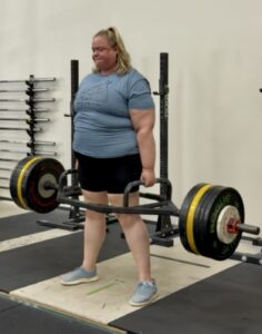 Woman performing hex bar deadlift with 175kg