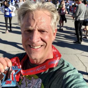 CJ holding medal at half marathon