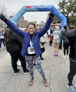Woman with arms raised at finish line of half marathon