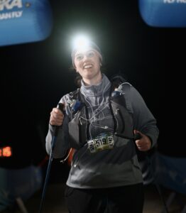 Woman with headlamp, crossing finish line of race