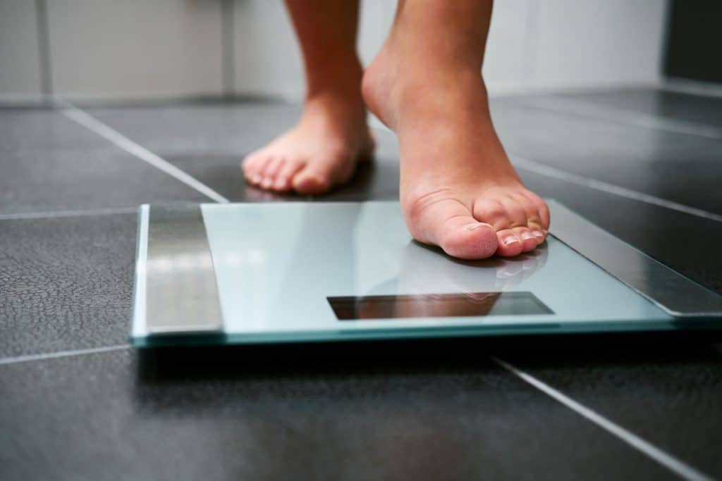 Female bare feet stepping on weight scale